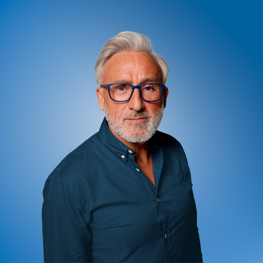 Man wearing blue reading glasses and a dark shirt against a blue background