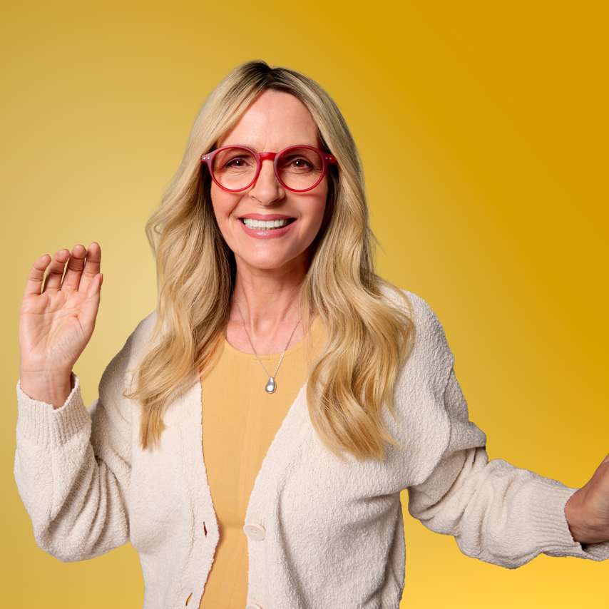 Woman wearing red glasses and a beige cardigan on a yellow background